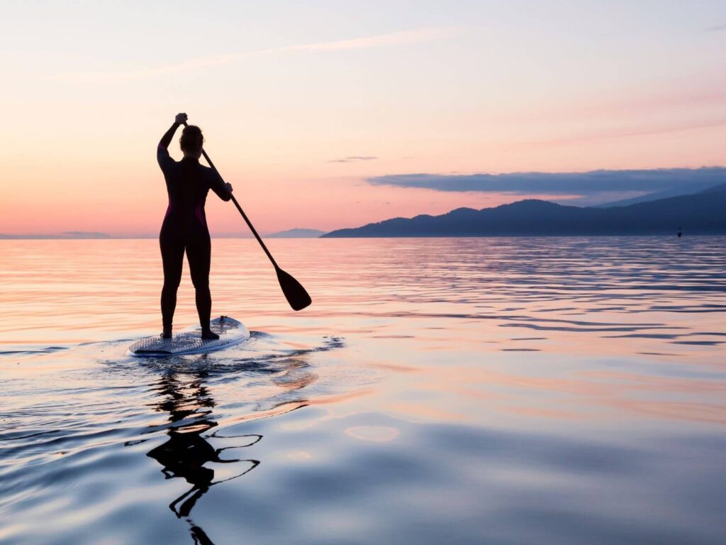 mulher fazendo stand up paddle em uma mar calmo